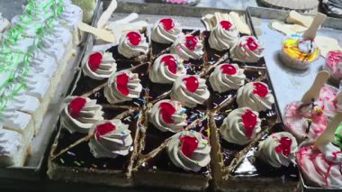 Yol kenarındaki raflar renkli hamur işleri ve kekler ile doludur, görünür dekoratif kremalarla düzenli olarak düzenlenmiştir..