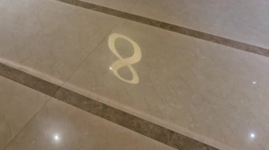 Yüzen altın harf 8 seramik zeminde yatıyor, altın parlaklığıyla desenli yansımaları birleştiriyor..