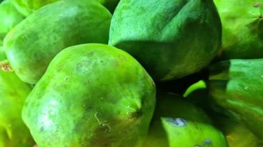 Taze yeşil papayalar bir dükkanda satılığa çıkarılıyor, olgunlaşmamış pürüzsüz bir ten ve doğal yeşil bir tonu gösteriyor..