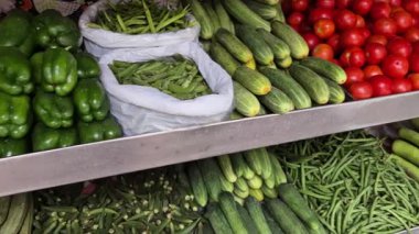 Bir sebze mağazası sebze, kapsiyum, salatalık, domates ve fasulye satar..