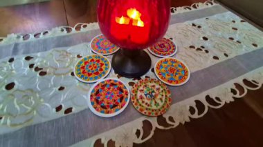 Elektrik mumları yuvarlak kırmızı bir kapta ışık yayar, yumuşak bir dekoratif ışıltı yaratır..