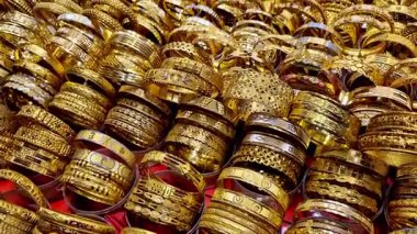 Altın kaplama, altın kaplama bilezikler yakın plan bir mücevher sergisinde, karmaşık oymalı desenler ve parlak dükkan aydınlatması altında zengin metalik parlaklığı gösteriyor.