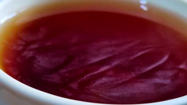 Canlı kırmızı kehribar koyu kahveye yakınlaşıyorum. Beyaz fincanın içinden yansıyan kıvrımlı, damar benzeri ışık desenlerini vurguluyorum..