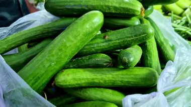 Sebze pazarında üst üste yığılmış taze yeşil salatalıklar yumuşak gün ışığında doğal renk değişimleriyle pürüzsüz ve parlak derileri gösteriyor..