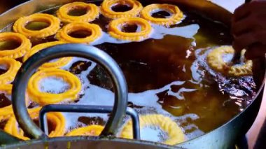 Halka şeklinde birkaç Jalebi imarti, büyük, derin bir yağ fıçısında fokurdarken görülüyor..