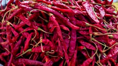 Büyük bir kurutulmuş kırmızı biber yığını çerçeveyi, buruşuk dokularını ve saplarını göstererek doldurur. Karabiberlerin koyu kırmızı renkleri tüm yığın boyunca canlı ve tutarlı..