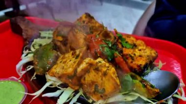 Cızırdayan Paneer Tikka, buharı yükselen kızgın bir demir tabakta servis yapıyordu. Tabakta öğütülmüş lahana yatağında marine edilmiş süzme peynir, biber ve soğan yer alıyor..