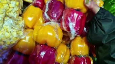 Kırmızı ve sarı dolmalık biberler perakende satışı için plastik filme sarılmış. Yüksek açılı çekimde paketlenmiş sebzelerin renkli ve parlak dokusunu gösteriyor..