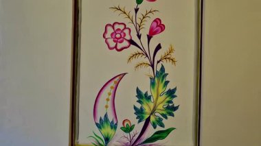Çerçeveli bir panelin içine pembe çiçekler, yeşil yapraklar ve dekoratif desenler çizilmiş renkli duvar resimleri. Jaipur 'da bir iç duvarda geleneksel el yapımı tasarım..