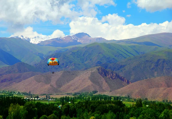 Parachute flying above green valley — Stock Photo, Image