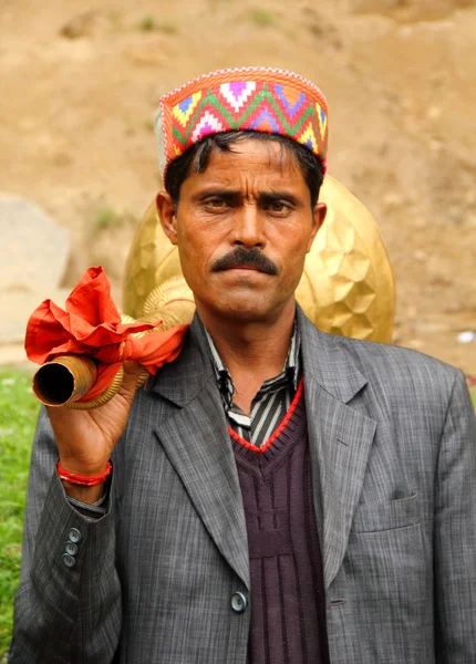 Indiase musicus gekleed in tribal hoed draagt een buis op zijn schouder Stockfoto