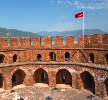 Bir Türk bayrağı ve mavi gökyüzü ile kırmızı tuğla kırmızı kule.
