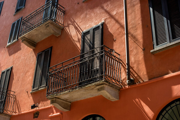 Traditional Italian balcony vykraski and terracotta walls. The windows shuttered, the balcony casts a shadow.