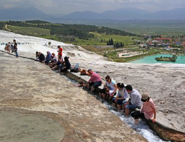 Pamukkale, Türkiye - 26 Nisan 2015: Traverten teraslarda gelen su akar dalmış turist ayak