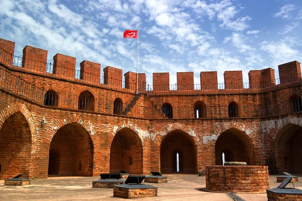 Bir Türk bayrağı ve mavi gökyüzü ile kırmızı tuğla kırmızı kule.