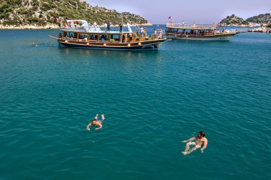 Kekova, Antalya, Türkiye - 26 Ağustos 2014:: Antalya, yat, yelkenli tekne ve çevresinde, parlak mavi gökyüzü arka plan üzerinde Yüzme insanlar görünümünü bir antik Likya bölgesi olan Kekova'nın deniz manzarası.