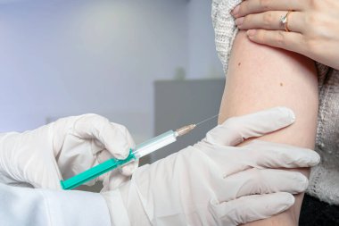 Doktor bir hastaya aşı içeren bir şırınga verir.