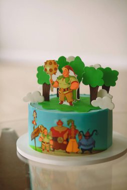 Çizgi film karakterleri ve orman temalı elementlerle süslenmiş parlak bir doğum günü pastası. Çocuklar için parti ve tatlı konsepti..