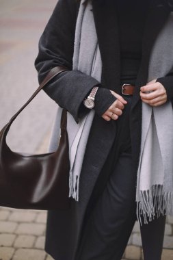 El çantası, kol saati ve palto içeren şık kıyafet detaylarının yakın çekimi. Modern moda yaşam tarzı ve zarif günlük aksesuar konsepti.