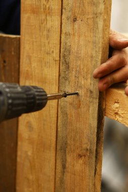 Tahtaya vida saplayan bir matkabın yakın çekimi. İnşaat işi, DIY onarımı ve marangozluk konsepti.