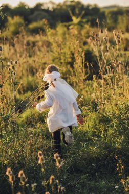 Genç kız altın saatinde vahşi bir yaz çayırında özgürce koşuyor. Beyaz bir gömlek giyer ve saçında büyük beyaz bir fiyonk takar, hareketle, özgürlükle ve çocukluk enerjisiyle dolu yumuşak bir kırsal yaşam tarzı yaratır..