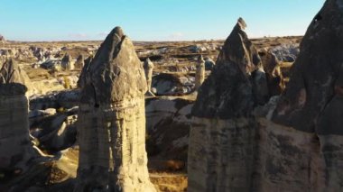 Türkiye 'nin Kapadokya bölgesinde taş oymalı dev kayalar ve gün batımına doğru at sırtında at süren insanlar