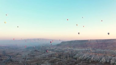 Sıcak hava balonları güneş doğarken Türkiye 'nin Kapadokya kayalık arazisinde uçuyor