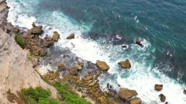 Gündüz vakti okyanus dalgalarıyla tropikal sahilde kayalar