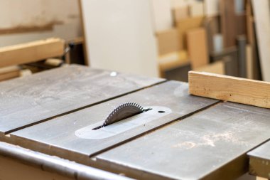 Marangoz ahşap işçisi atölyede mobilya yapmak için endüstriyel elektrikli odun kesme makinesiyle odun kesiyor.