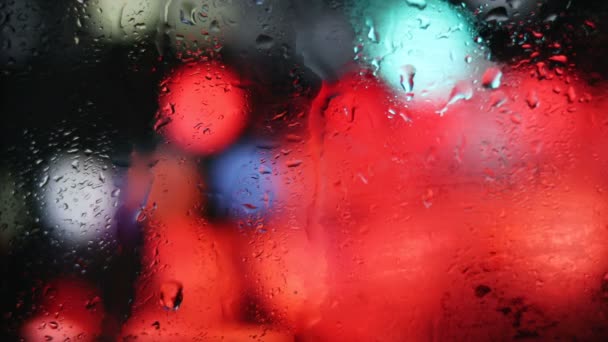 Regndroppar Som Flyter Det Dimmiga Glaset Suddiga Nattstadsljus Bakgrunden Regnigt — Stockvideo