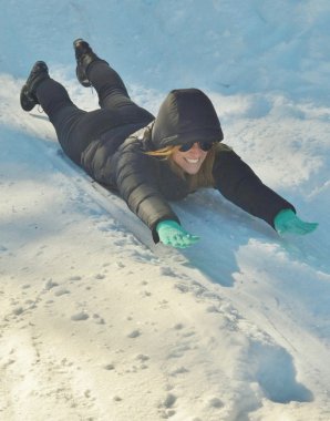 Genç kadın bir karlı tepeden aşağı kayar.