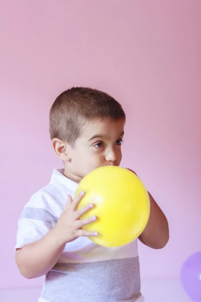 Мальчик надувает воздушный шар — стоковое фото