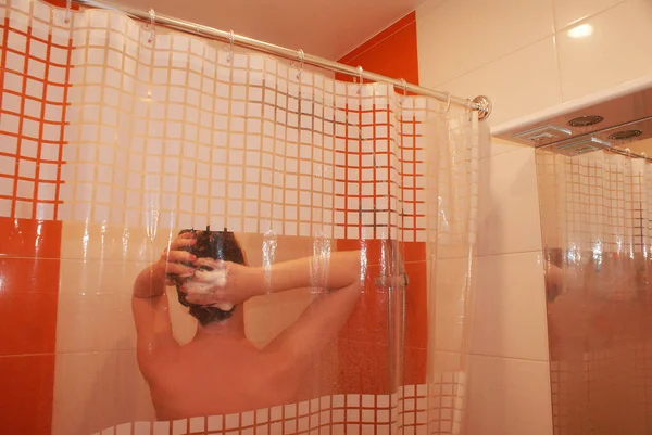 女の子はシャワーヘッドからシャワーを浴びますバスルームのホルダーに固定 — ストック写真