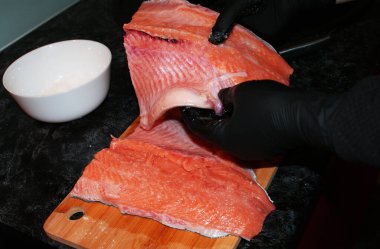 Eldivenli kadın eller mutfakta kırmızı balık kesiyor..