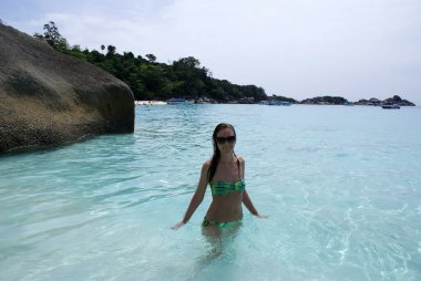 Genç bir kadın bir cennet adasında dinleniyor ve okyanusta yüzüyor..