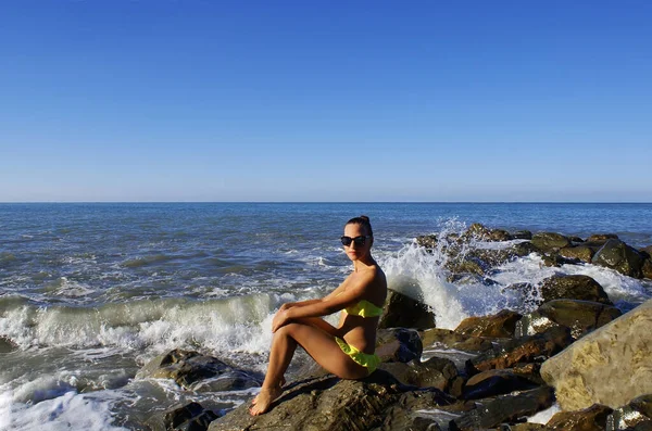 Egy Fiatal Pihen Miközben Egy Kövön Óceán Partján Bikiniben — Stock Fotó