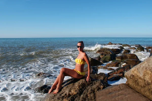 Egy Fiatal Pihen Miközben Egy Kövön Óceán Partján Bikiniben — Stock Fotó