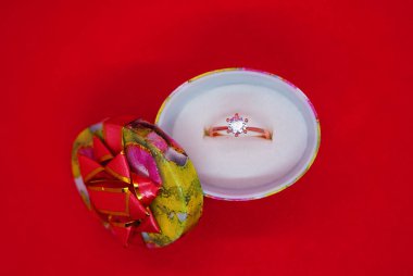 Hediye, altın yüzük, kırmızı arka plandaki hediye kutusunda elmaslar.