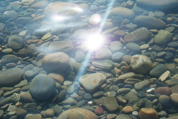 Güneş suda parlıyor, deniz tabanında çakıl taşları, doğa..