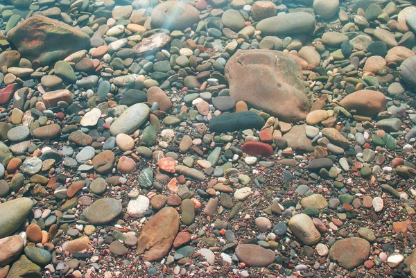 太陽は水の上にぎらつき 海底の小石 — ストック写真
