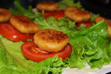 Domates ve marulun üstünde kızarmış nugget, mutfakta pişirme..