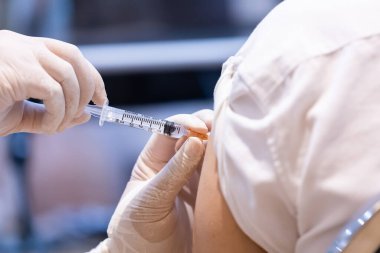 Doktor tarafından tek kullanımlık plastik şırınga ile hastanın koluna enjekte edilen kovid 19 aşısı bağışıklık sistemini inaktif ya da adenovirüs virüsü ile güçlendirir.