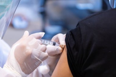 Doktor tarafından tek kullanımlık plastik şırınga ile hastanın koluna enjekte edilen kovid 19 aşısı bağışıklık sistemini inaktif ya da adenovirüs virüsü ile güçlendirir.