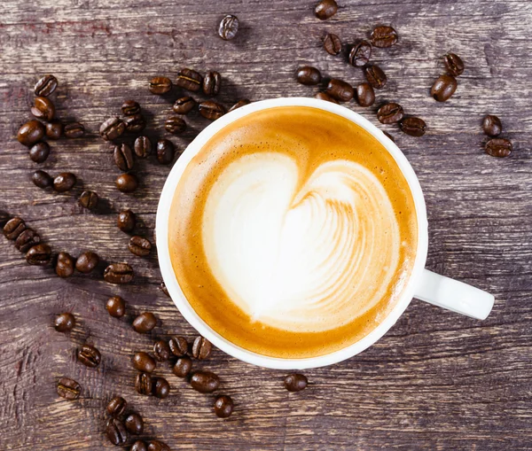 Tasse Kaffee und geröstete Bohnen auf altem Holztisch — Stockfoto