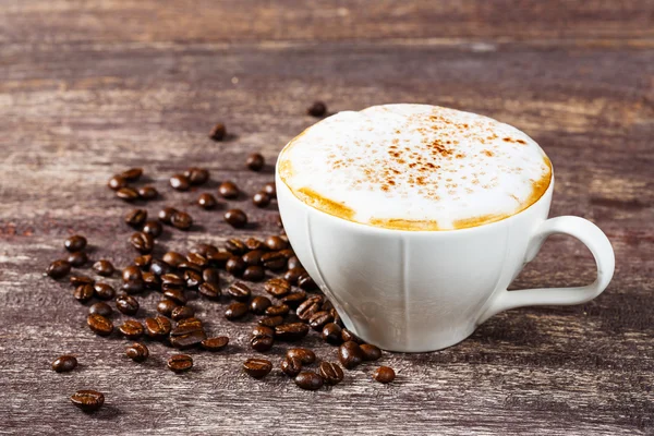 Xícara de café e feijão assado na mesa de madeira velha — Fotografia de Stock