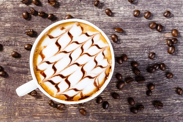 Tasse Kaffee und geröstete Bohnen auf altem Holztisch — Stockfoto