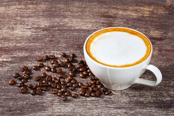 Xícara de café e feijão assado na mesa de madeira velha — Fotografia de Stock