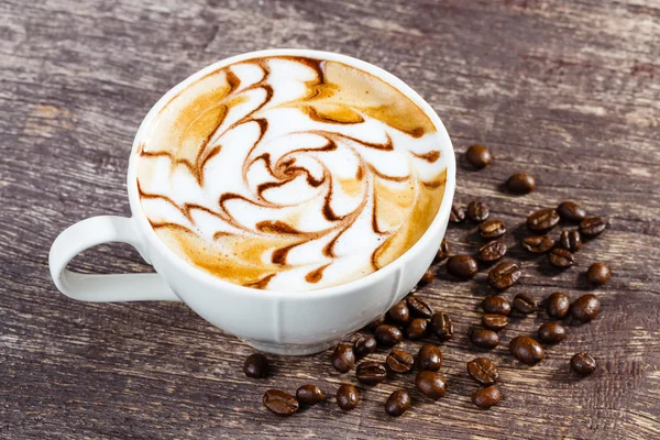 Tasse Kaffee und geröstete Bohnen auf altem Holztisch — Stockfoto