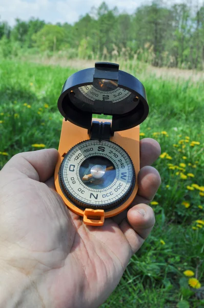 Kompas w ręku, na tle kwitnące łąki. — Zdjęcie stockowe