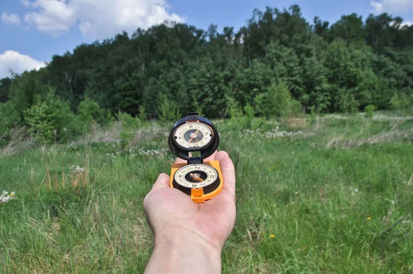 Kompas in de hand, tegen de achtergrond van het bos. — Stockfoto